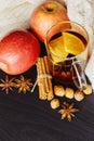 Glass cup of hot spicy drink with apple and orange slices, cinnamon and anise on dark brown background Royalty Free Stock Photo