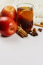 Glass cup of hot spicy tee with apple slices, cinnamon and anise on white knitted background with copy space Royalty Free Stock Photo