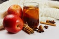 Glass cup of hot spicy tee with apple slices, cinnamon and anise on white knitted background with copy space Royalty Free Stock Photo