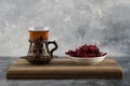 A glass cup of hot tea with dried flowers on a wooden cutting board