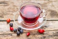 Glass Cup of karkade tea with wild berries on wood background Royalty Free Stock Photo