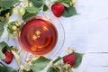 Glass cup of linden tea with linden flowers, leaves and strawberries on an old white wooden table Royalty Free Stock Photo