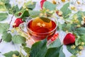 Glass cup of linden tea with linden flowers, leaves and strawberries on an old white wooden table Royalty Free Stock Photo