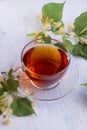 Glass cup of linden tea, and linden flowers on a white wooden table Royalty Free Stock Photo