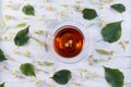Glass cup of linden tea, and linden flowers on a white wooden table Royalty Free Stock Photo