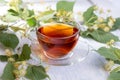 Glass cup of linden tea, and linden flowers on a white wooden table Royalty Free Stock Photo