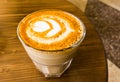 A glass cup of milk coffee stands on the table, the view from above.