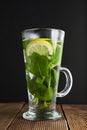 Glass Cup of mint tea ith lemon slices and yellow flowers on background. Wooden table and black background. Royalty Free Stock Photo