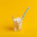 Glass cup with paper tube and marshmallows on a yellow background. Minimalistic concept