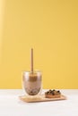 A glass cup of pearl milk tea also called bubble tea and a plate of tapioca ball on yellow background Royalty Free Stock Photo