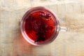 A glass cup with red hibiscus tea stands on a wooden table. Royalty Free Stock Photo