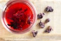 A glass cup with red hibiscus tea stands on a wooden table. Royalty Free Stock Photo