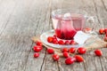 Glass cup of rosehip herbal tea with tea bag and rose hip fruits on wooden rustic backdrop