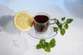 Glass cup of strong black tea on a beautiful blue ice with yellow lemon and green mint. Royalty Free Stock Photo