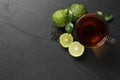 Glass cup of tasty bergamot tea, dry leaves and fresh fruits on black table, flat lay. Space for text Royalty Free Stock Photo