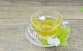 Glass cup with tea and fresh jasmine flowers on wooden table