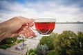 A glass cup with tea in hand against a background of urban morning scenery.