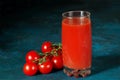 Glass cup with tomato juice and cherry tomatoes on a dark blue textural background Royalty Free Stock Photo