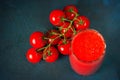 Glass cup with tomato juice and cherry tomatoes on a dark blue textural background. top view Royalty Free Stock Photo