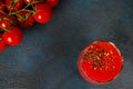 Glass cup with tomato juice with ground black pepper and cherry tomatoes on dark background. top view Royalty Free Stock Photo