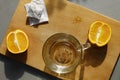 Glass cup, two orange slices, tea bag and wooden cutting board on gray kitchen background Royalty Free Stock Photo