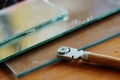 Glass cutter and glass sheet on wooden background