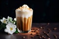 Glass of Dalgona Coffee with whipped cream and caramel on dark background with white flowers, trendy coffee drink. Coffee latte Royalty Free Stock Photo