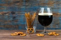 Glass of dark beer and pretzel snacks on wooden background