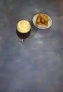 Glass of dark beer with white foam and a plate with fresh wheat croutons on a gray background Royalty Free Stock Photo