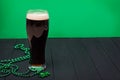 Glass of dark stout beer and traditional clover shaped decor