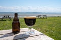 Glass of dark strong belgian beer served on outdoor terrace with green grass meadow on background Royalty Free Stock Photo