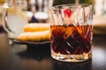 Glass of dark vermouth drink with slice of orange on a bar table outdoors, a popular aperitif, during a summer day with snacks and Royalty Free Stock Photo