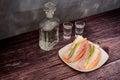 A glass decanter and two glasses of Russian vodka and a plate with two sandwiches with smoked meat on a wooden table Royalty Free Stock Photo