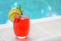 Glass of delicious cocktail near swimming pool, space for text. Refreshing drink Royalty Free Stock Photo