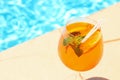 Glass of cocktail near swimming pool, space for text. Refreshing drink Royalty Free Stock Photo