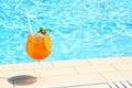 Glass of cocktail near swimming pool, space for text. Refreshing drink Royalty Free Stock Photo