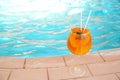 Glass of cocktail near swimming pool, space for text. Refreshing drink Royalty Free Stock Photo