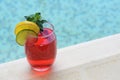Glass of delicious cocktail near swimming pool, space for text. Refreshing drink Royalty Free Stock Photo