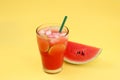 Glass of delicious drink with lime slices, ice cubes and fresh watermelon on yellow background Royalty Free Stock Photo