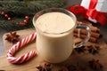 Glass of delicious eggnog, candy cane and anise stars on wooden table, closeup Royalty Free Stock Photo