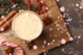 Glass of delicious eggnog on wooden table, flat lay. Bokeh effect