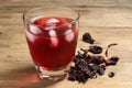 Glass of delicious iced hibiscus tea and dry flowers on wooden table, closeup Royalty Free Stock Photo