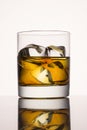 Glass of delicious whiskey with ice cubes on a gray background