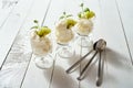 Glass of dessert with whipped cream with a fresh mint leaf and kiwi fruit on white table. Royalty Free Stock Photo