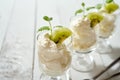 Glass of dessert with whipped cream with a fresh mint leaf and kiwi fruit on white table. Royalty Free Stock Photo