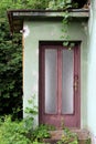 Glass with dilapidated wooden frame abandoned family house entrance doors locked with padlock mounted on wall with damaged facade