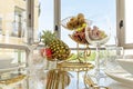 A glass dining table with a gold fruit bowl with pineapple, grapes of various kinds