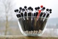 A glass dish with black globule ballpoint pens with a red one