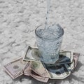 The glass is on dollars and on large pieces of salt, drinking water is poured into it Royalty Free Stock Photo