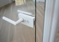 Glass Door handle. Glass door knob with handle in open glass door modern room with wooden floor Royalty Free Stock Photo